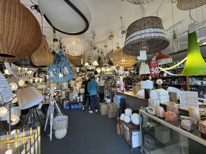 An aisle of the Cosmo Lighting showroom lined with lit rattan and glass pendants