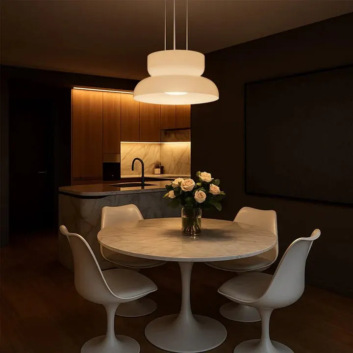 A dark kitchen and dining table lit by pendants and under-cabinet strip lighting